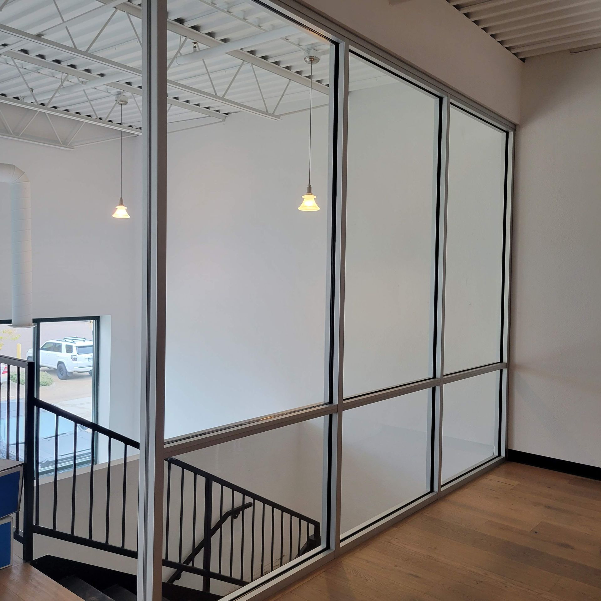 Interior view of a commercial space with a staircase, large windows, and a white ceiling.