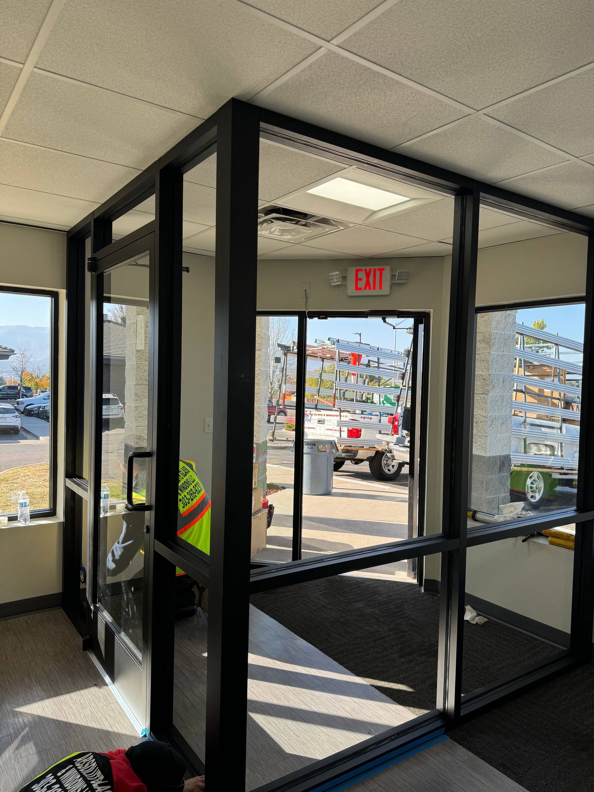 Black-framed glass entry door with exit sign above, visible commercial setting.