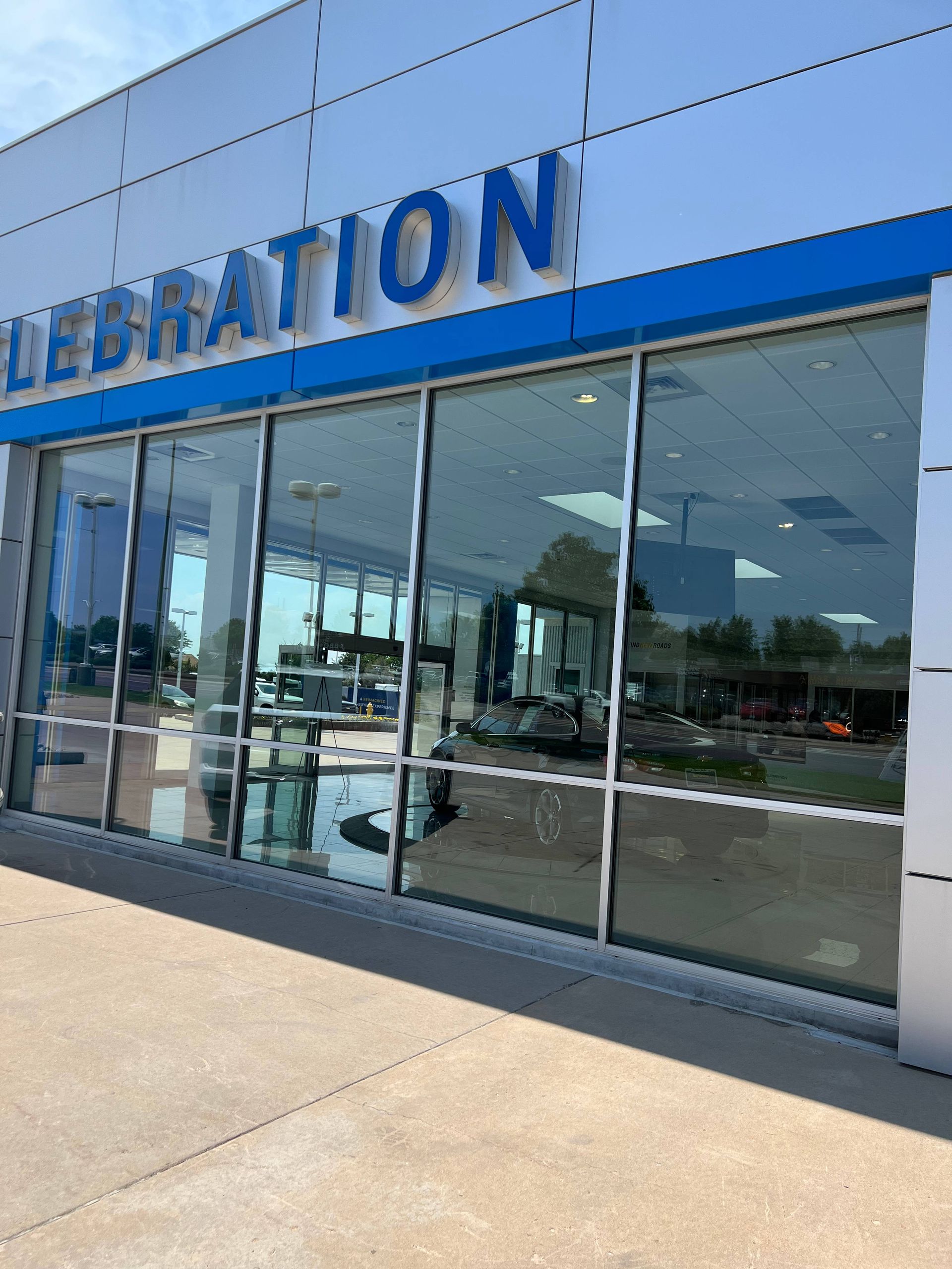 Celebration dealership with large windows, blue accents, and sign at top.