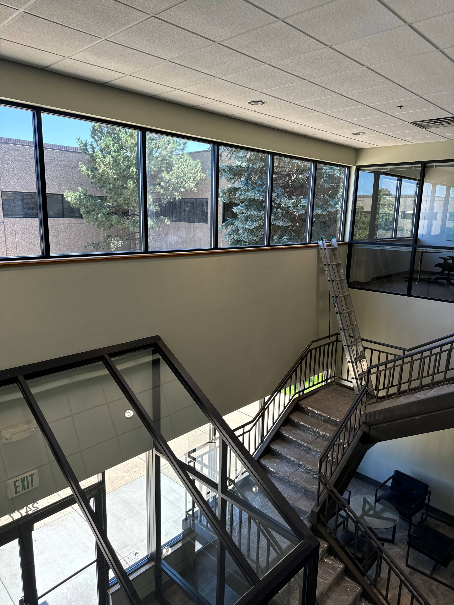 Interior view of a two-story building with stairs, windows, and natural light.