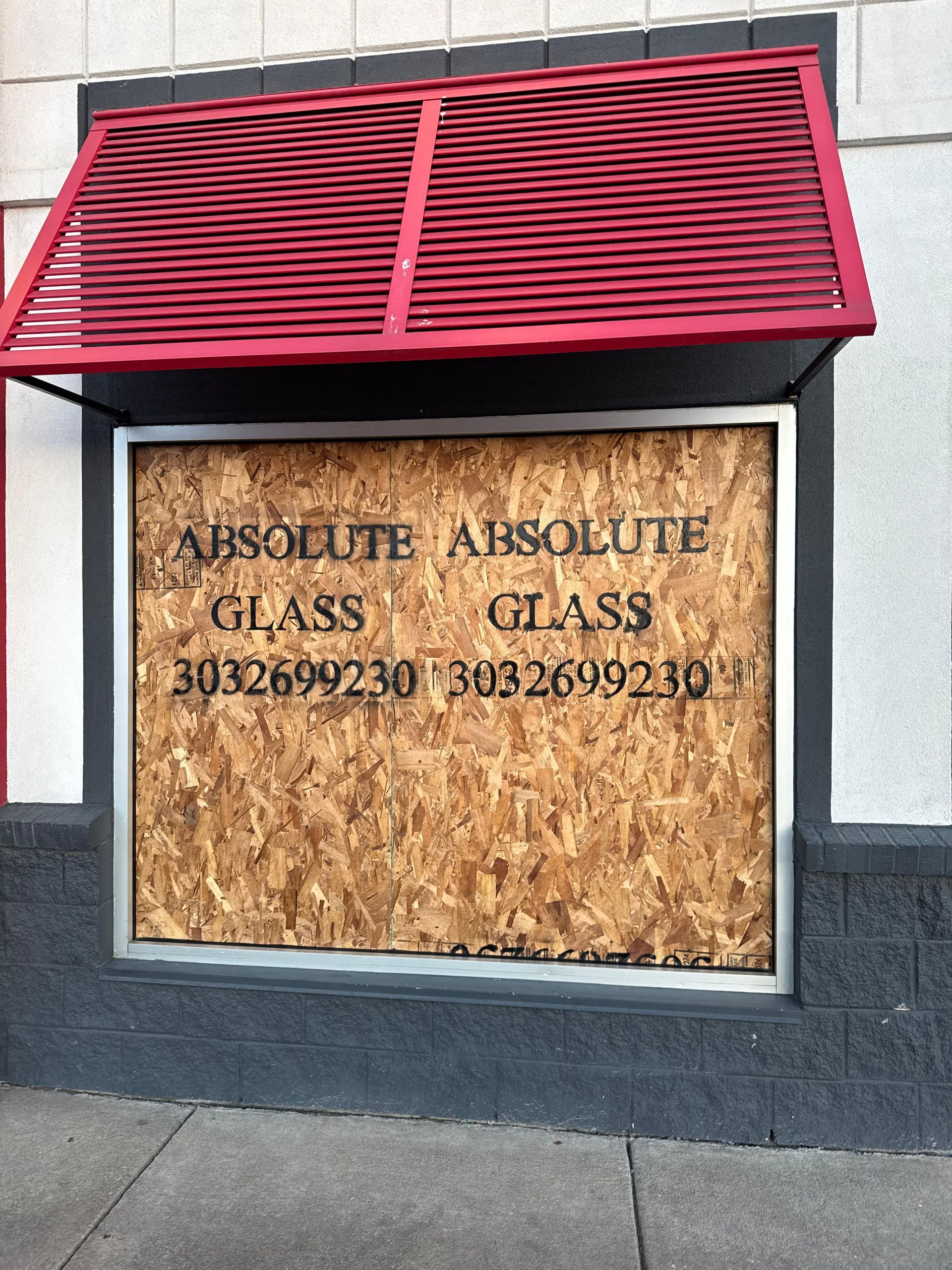 Boarded-up business with red awning; signs read 