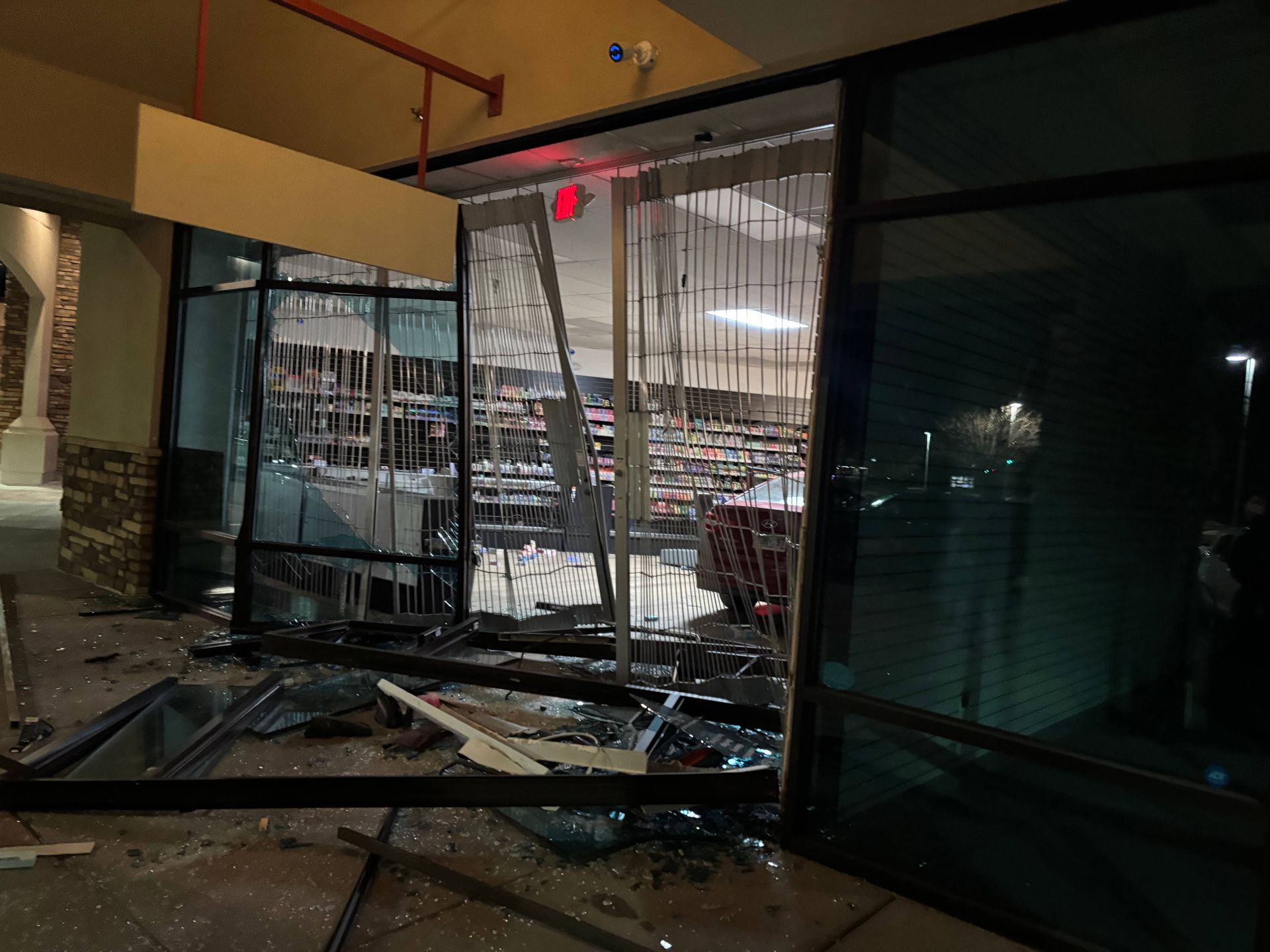 Storefront with shattered glass; a possible break-in or vandalism. Dark, nighttime scene. Debris on the ground.