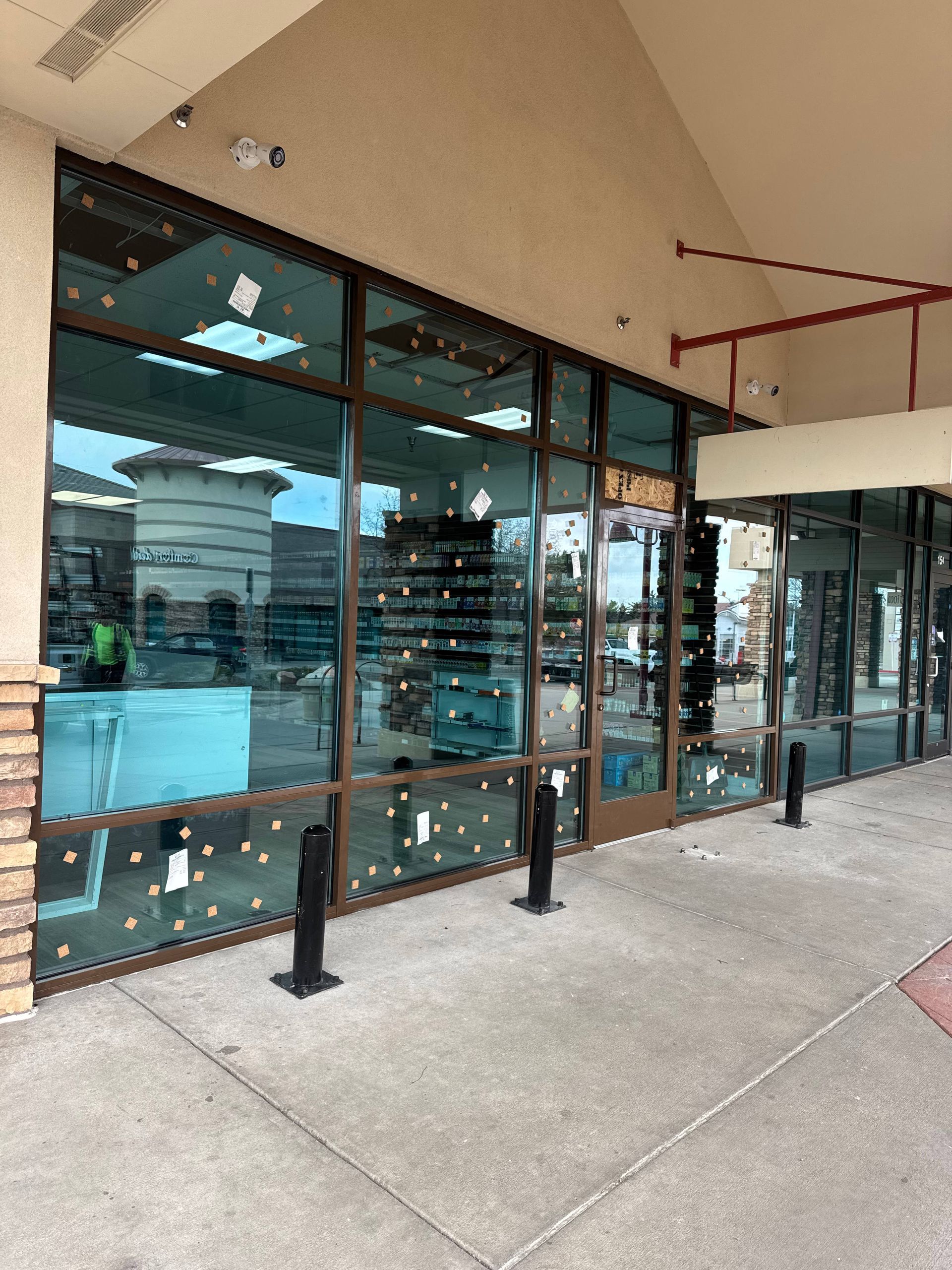 Storefront with large windows, security bollards, and a concrete walkway.