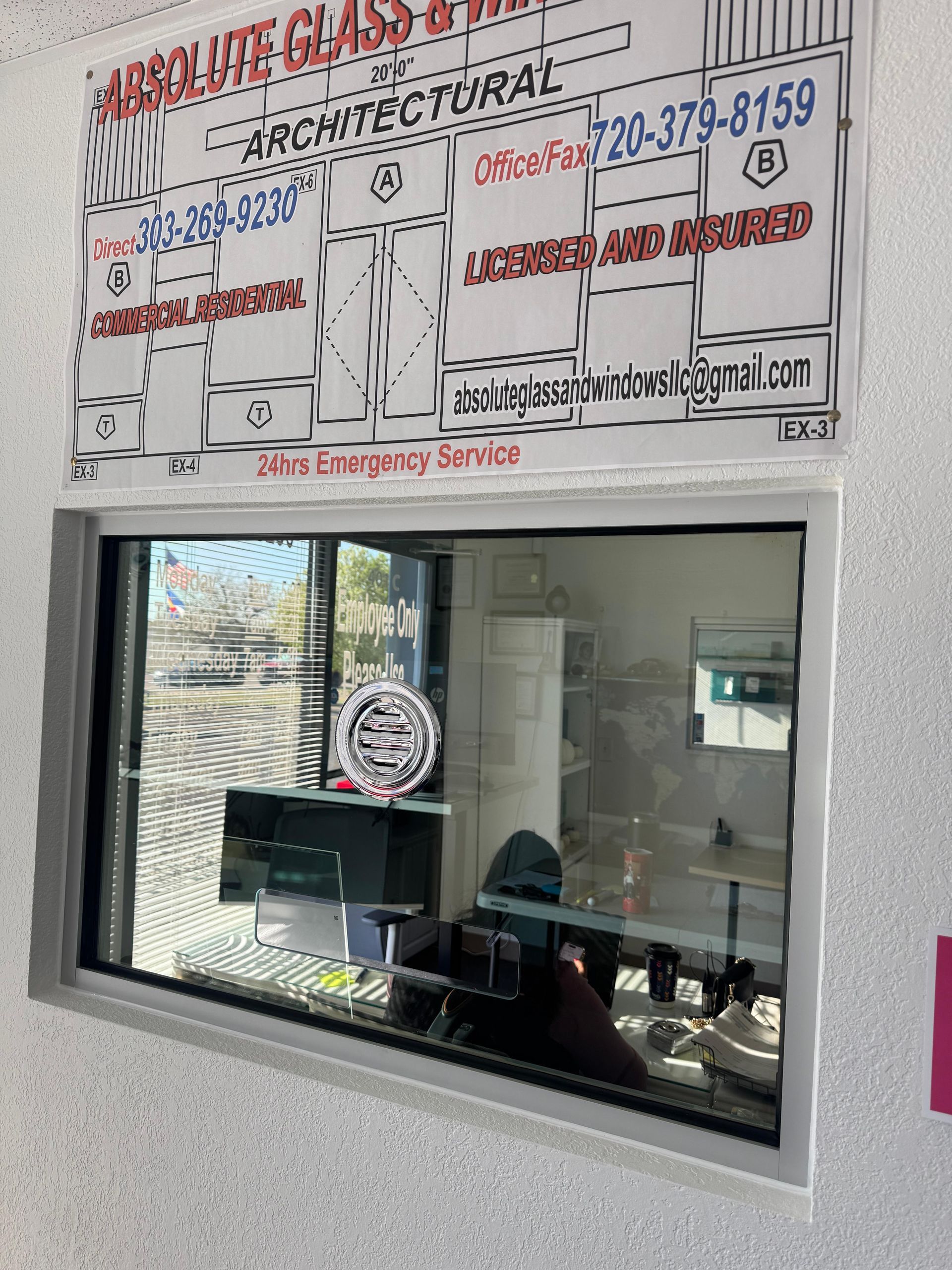 Window with a sign above it. Office interior visible through the glass.