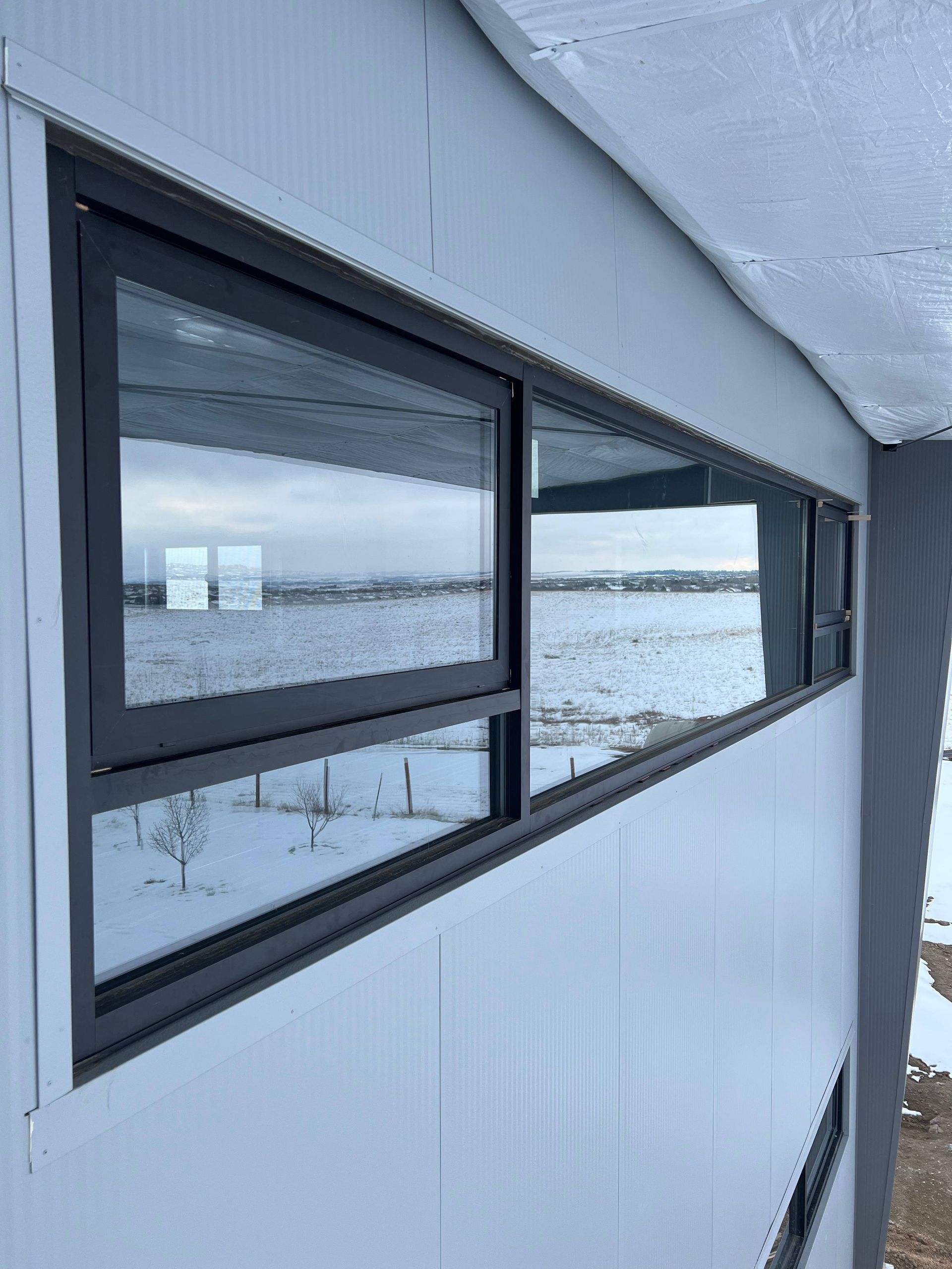 Dark-framed windows on a white building side, reflecting a snowy landscape.