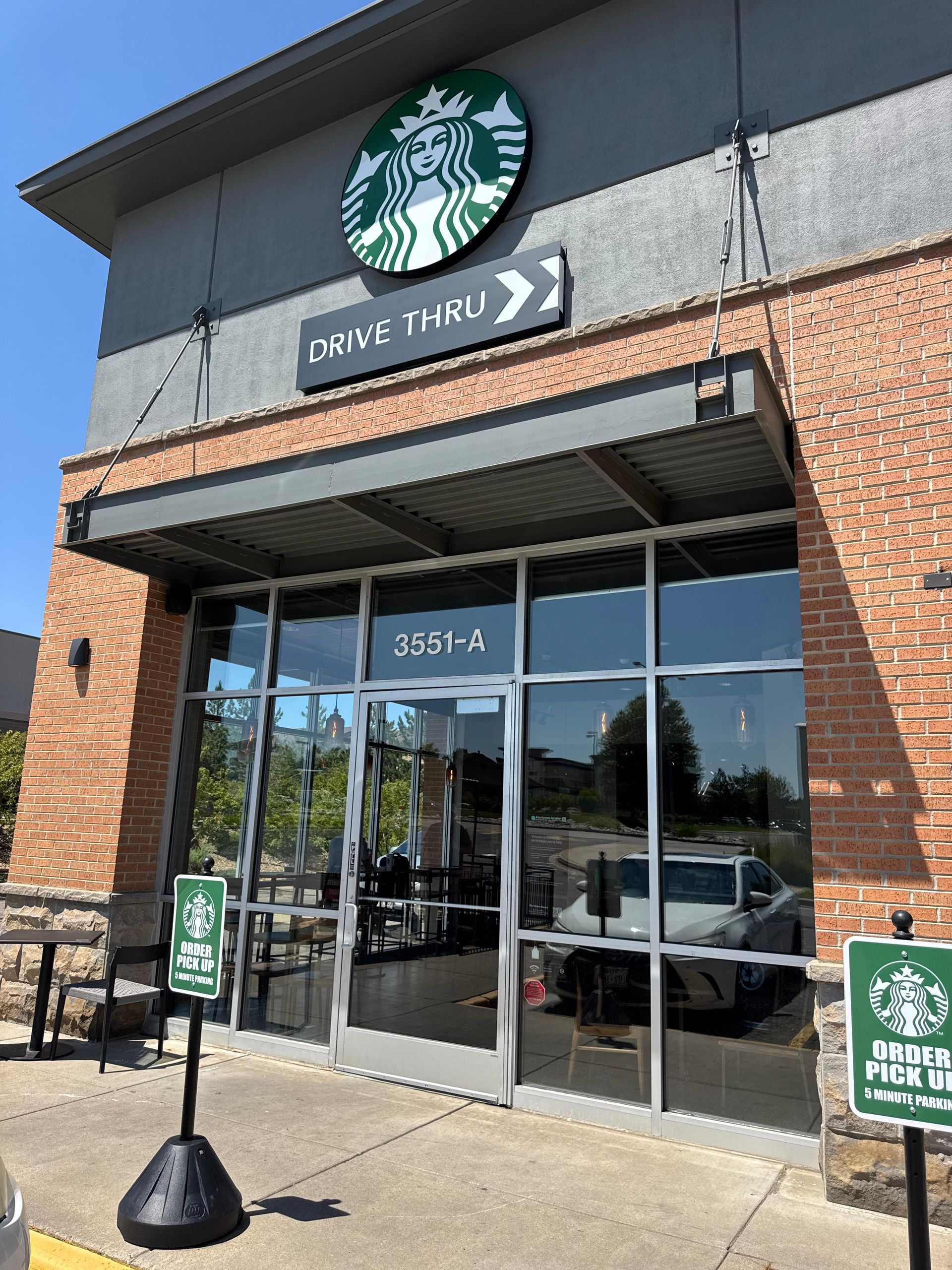 Starbucks store front with drive-thru. Features logo, door, and signs.