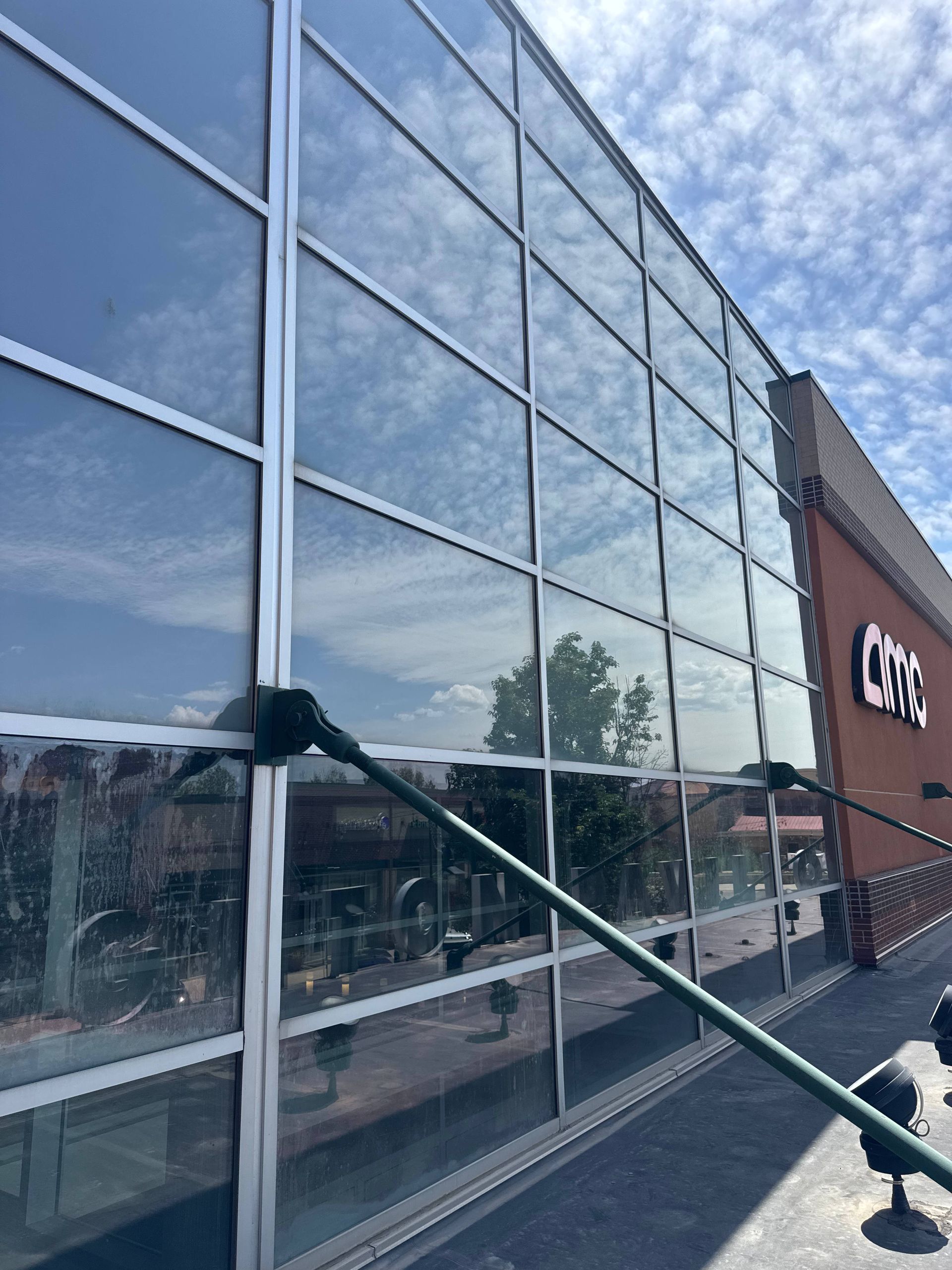 Large glass windows on a building with a clear sky reflected. A sign reading 