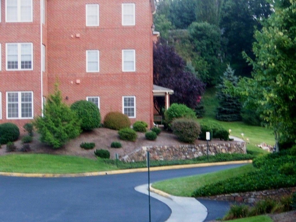 Brick apartment building with landscaping and winding road.
