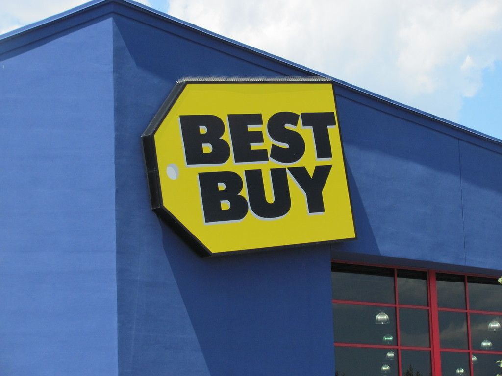 Best Buy store sign on a blue building; yellow sign with black lettering.