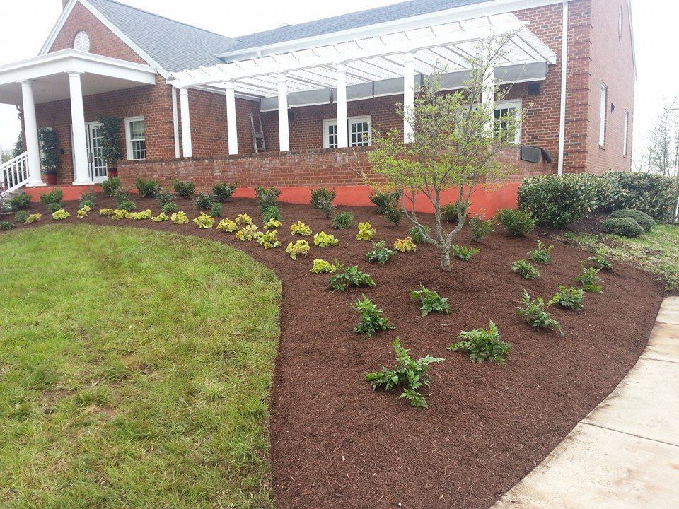 Brick house with landscaped flowerbeds and lawn. Mulch beds contain shrubs.