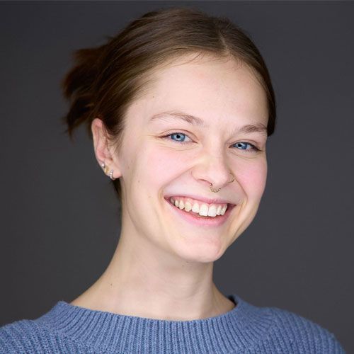 A person with blue eyes, smiling, wearing a blue sweater.