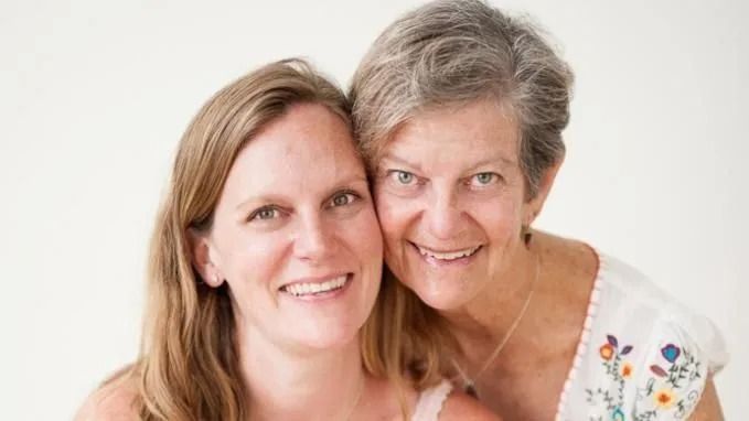 Woman with blonde hair and a woman with short gray hair smiling and embracing.