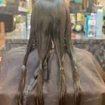 a woman is getting her hair cut at a salon.