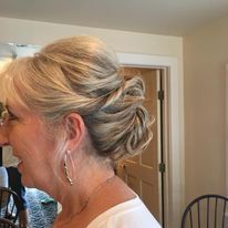 a woman is wearing a white shirt and earrings and has her hair in a bun.