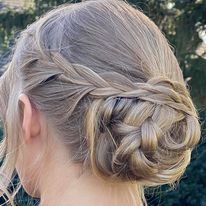 a woman is wearing her hair in a braided bun.