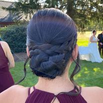 a woman in a purple dress is wearing a braided bun.