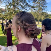 a woman with a braided bun is standing next to a group of bridesmaids.