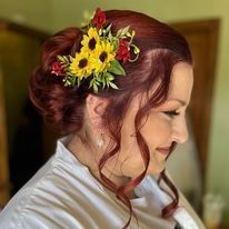a woman with red hair is wearing a bun with flowers in her hair.