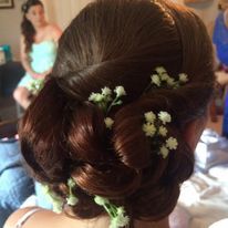 a woman is wearing her hair in a bun with flowers in it.