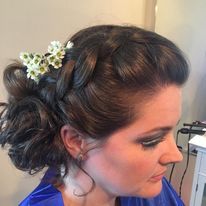 a woman is wearing a braided bun with flowers in her hair.