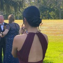 a woman in a burgundy dress is standing in a field.