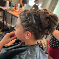 a little girl is getting her hair done in a salon.