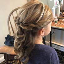 a woman is sitting in a chair with her hair in a half up half down hairstyle.