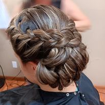a woman is getting her hair done in a braided bun.