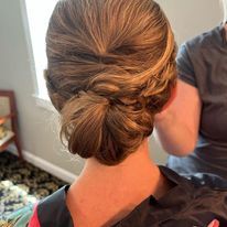 a woman is getting her hair done in a bun.