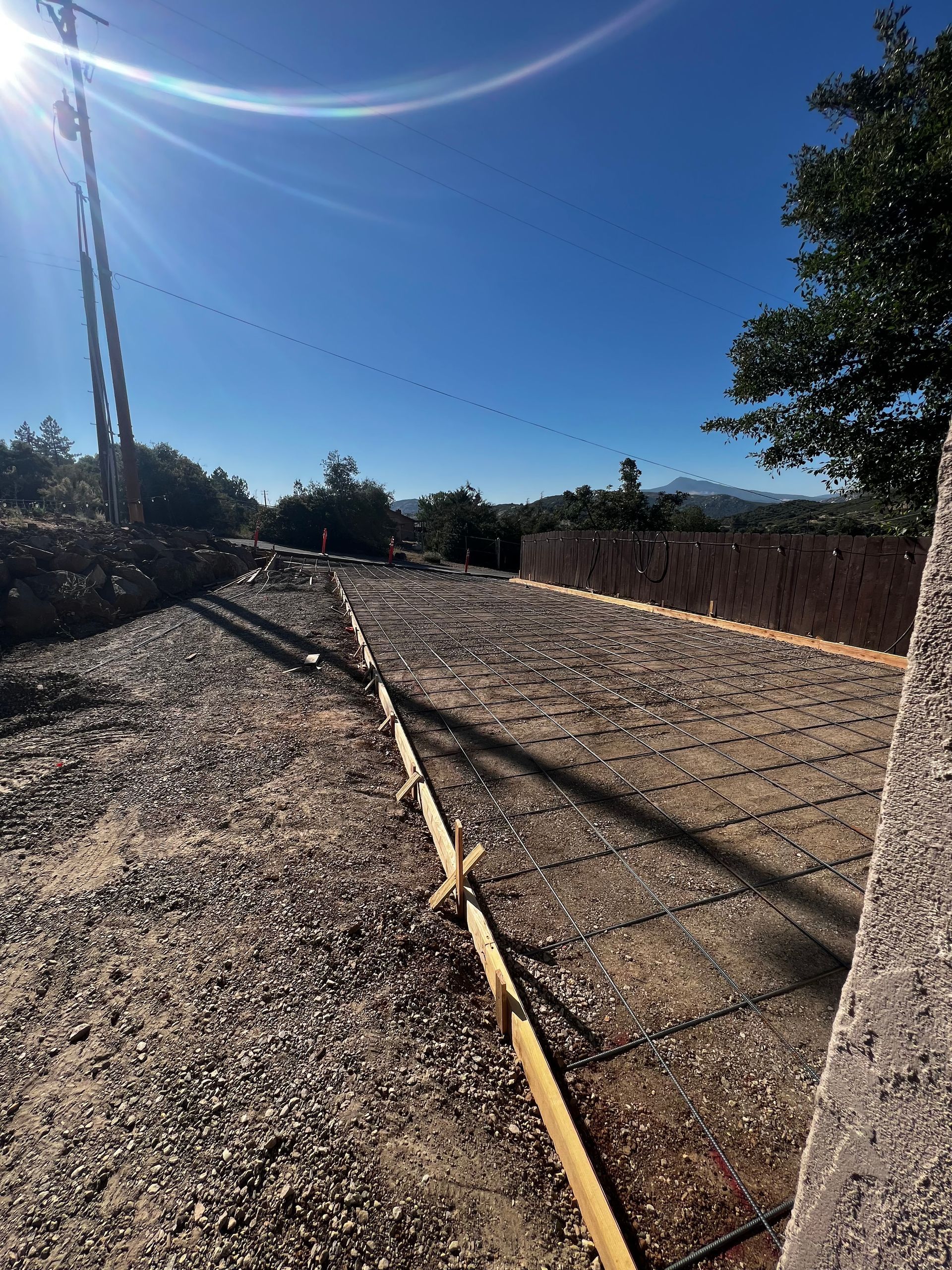 A dirt road with a barbed wire fence on the side of it