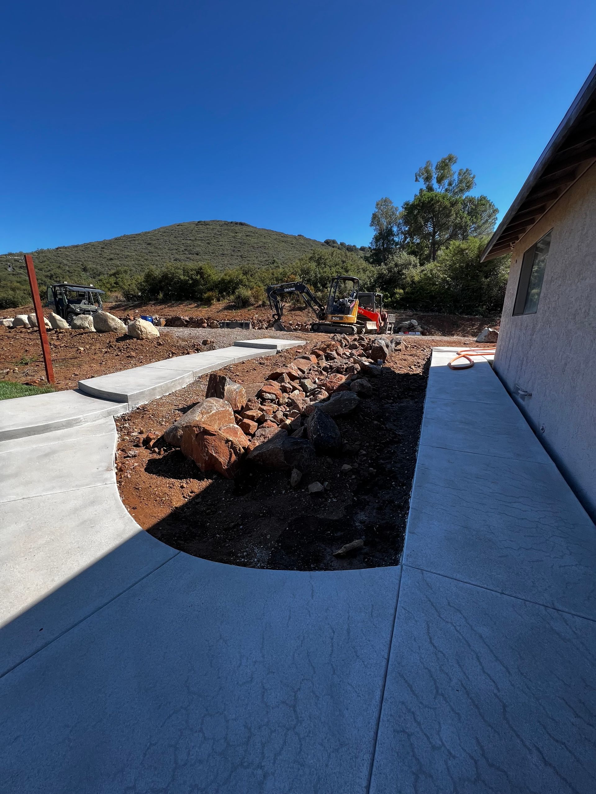 A concrete walkway leading to a house with a mountain in the background