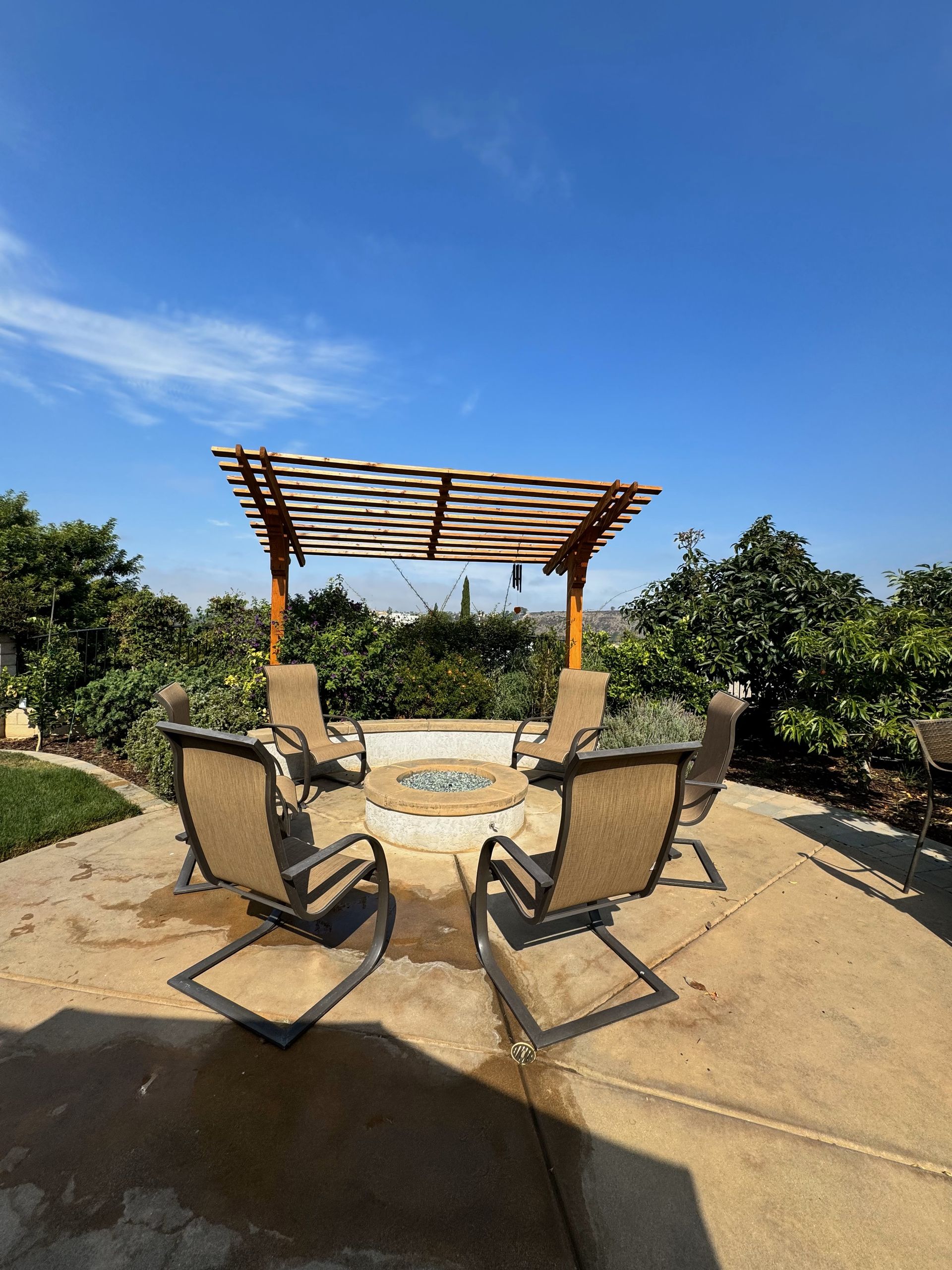 A patio with chairs and a fire pit under a pergola