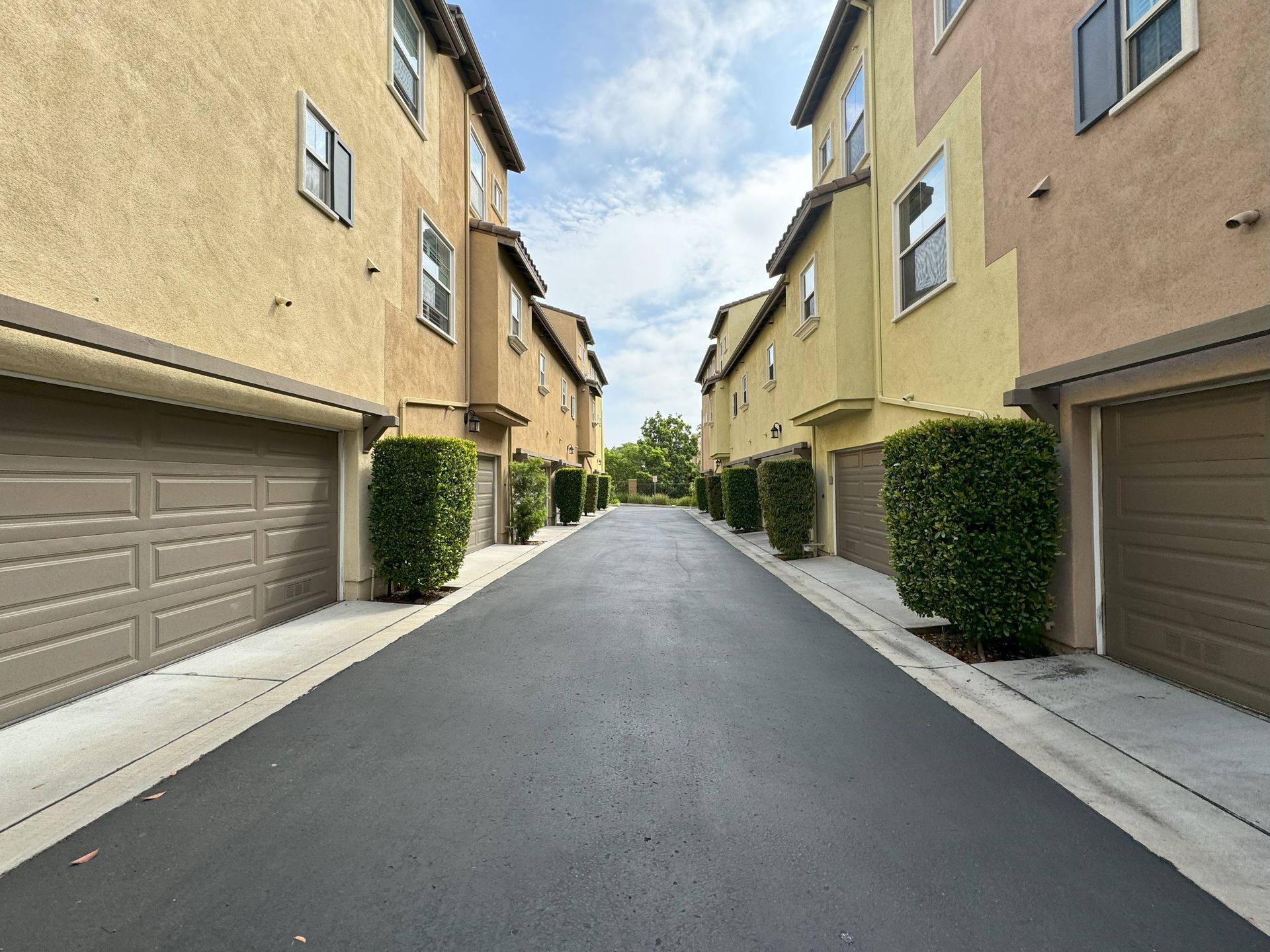 A narrow road between two apartment buildings with garage doors