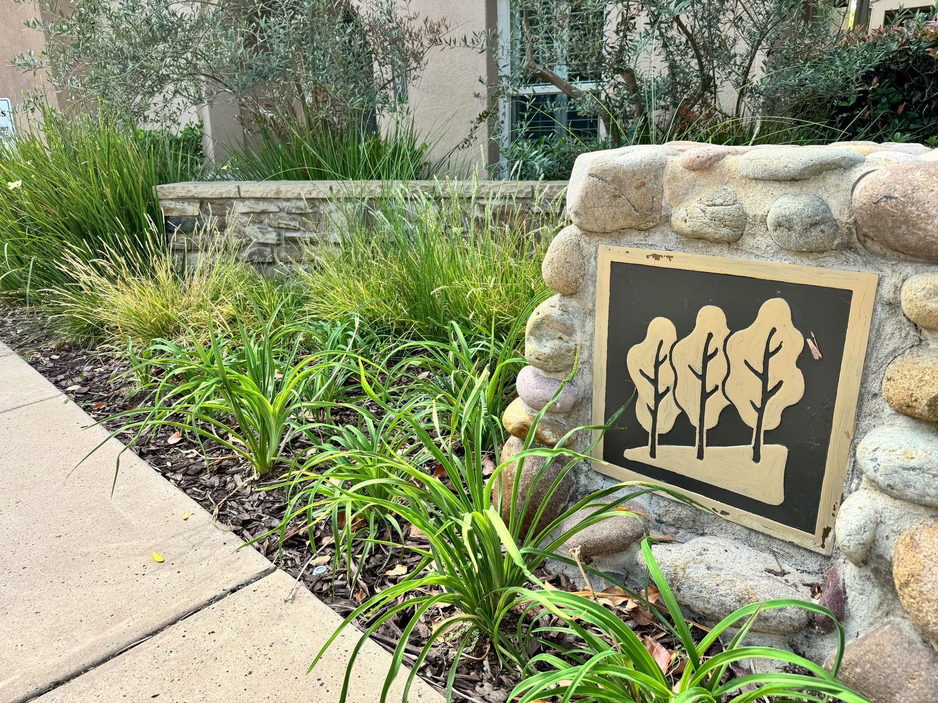 A stone wall with a sign that says trees on it
