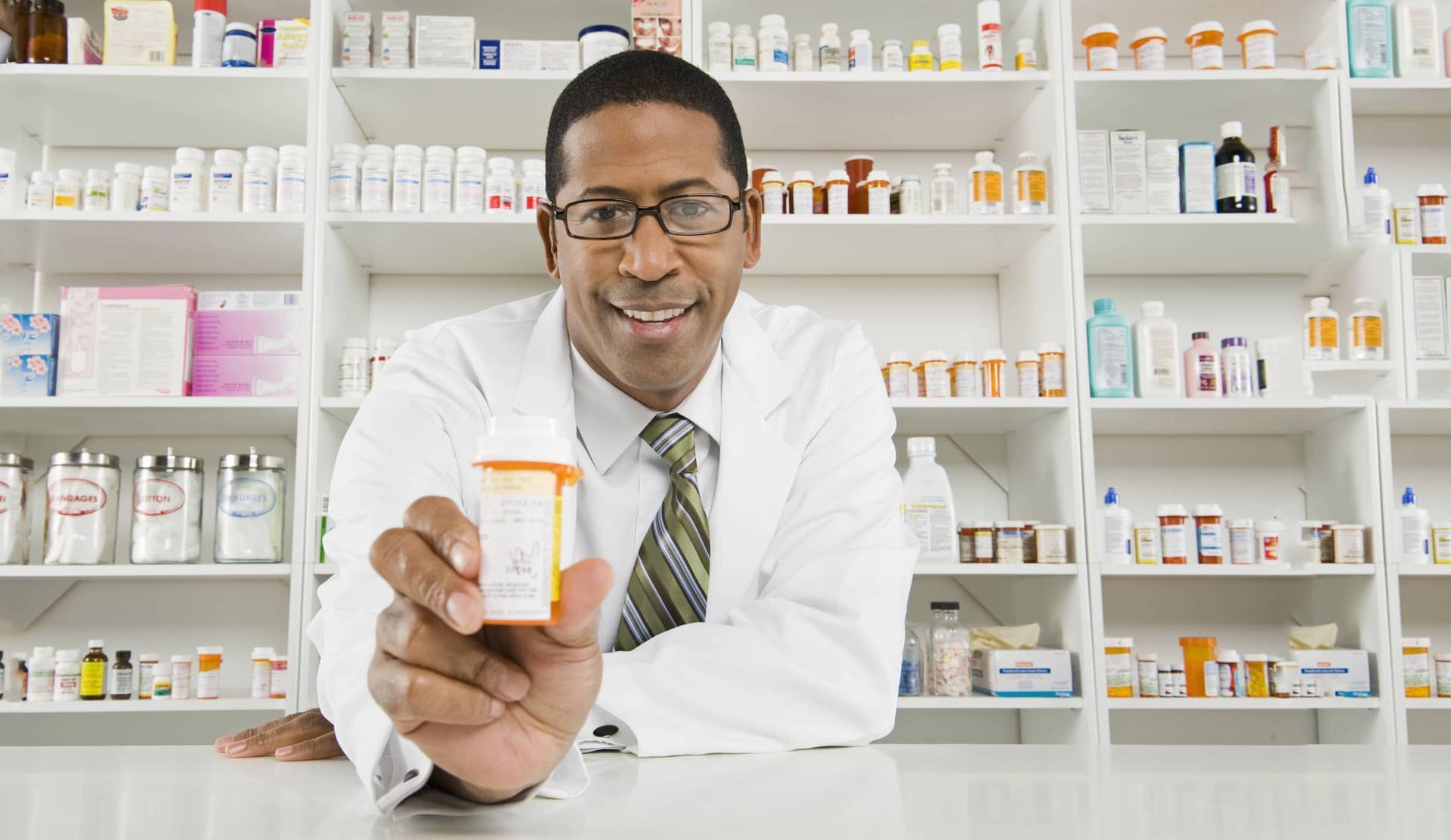 A pharmacist is holding a bottle of pills in a pharmacy.
