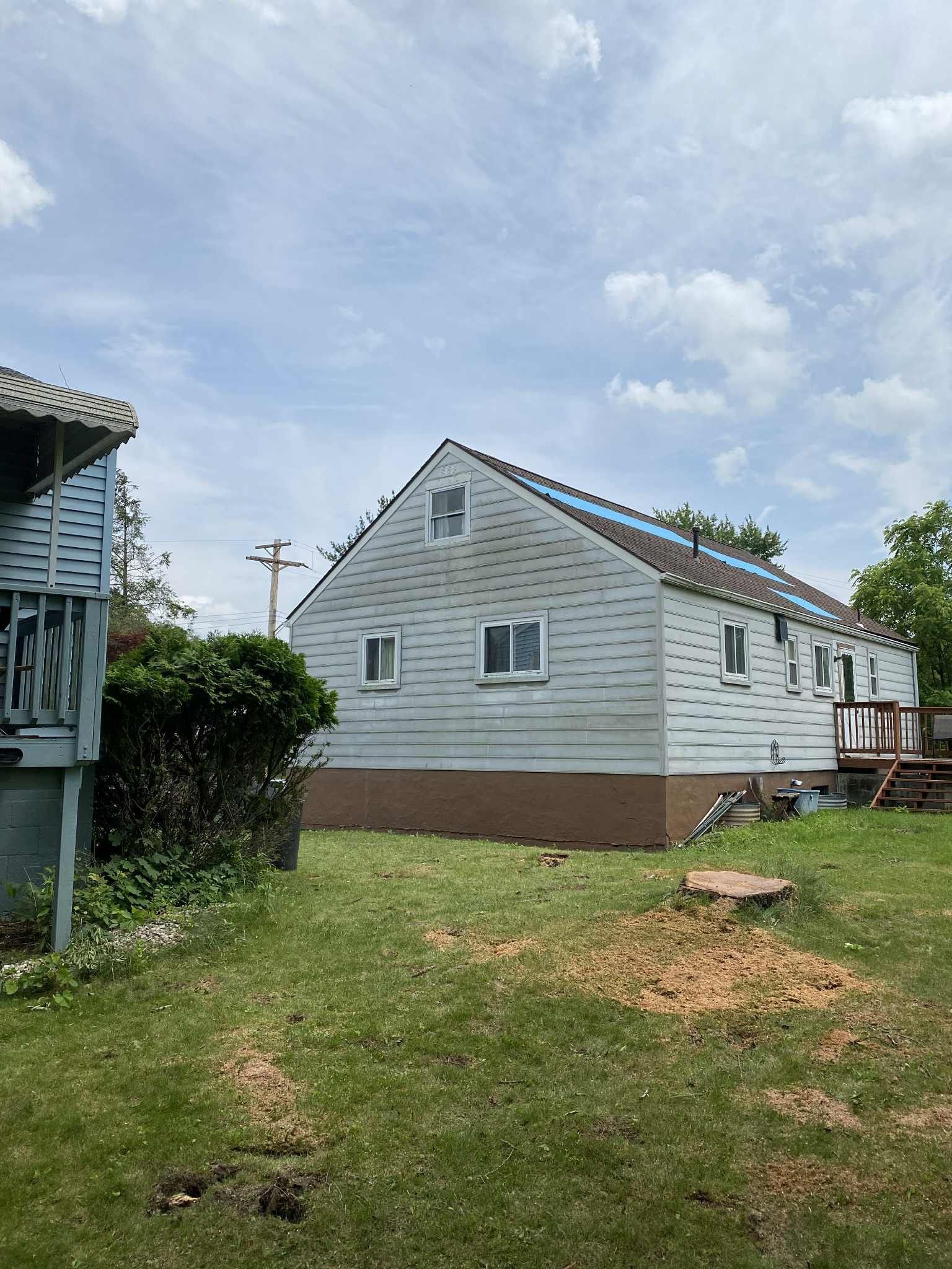 Side view of a light blue house, partially under construction, with green grass and sky.