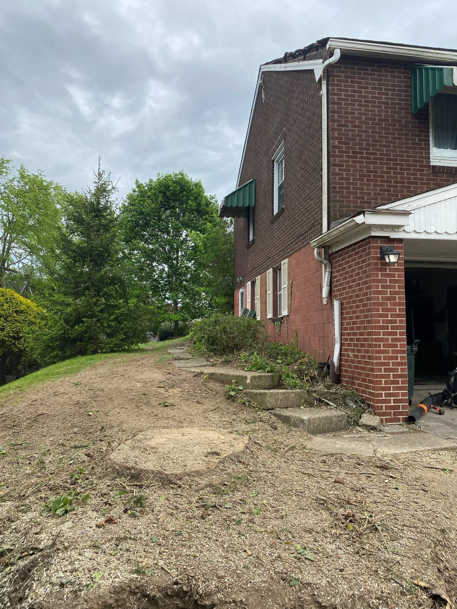 Brick house with steps leading up a hill; overcast sky.