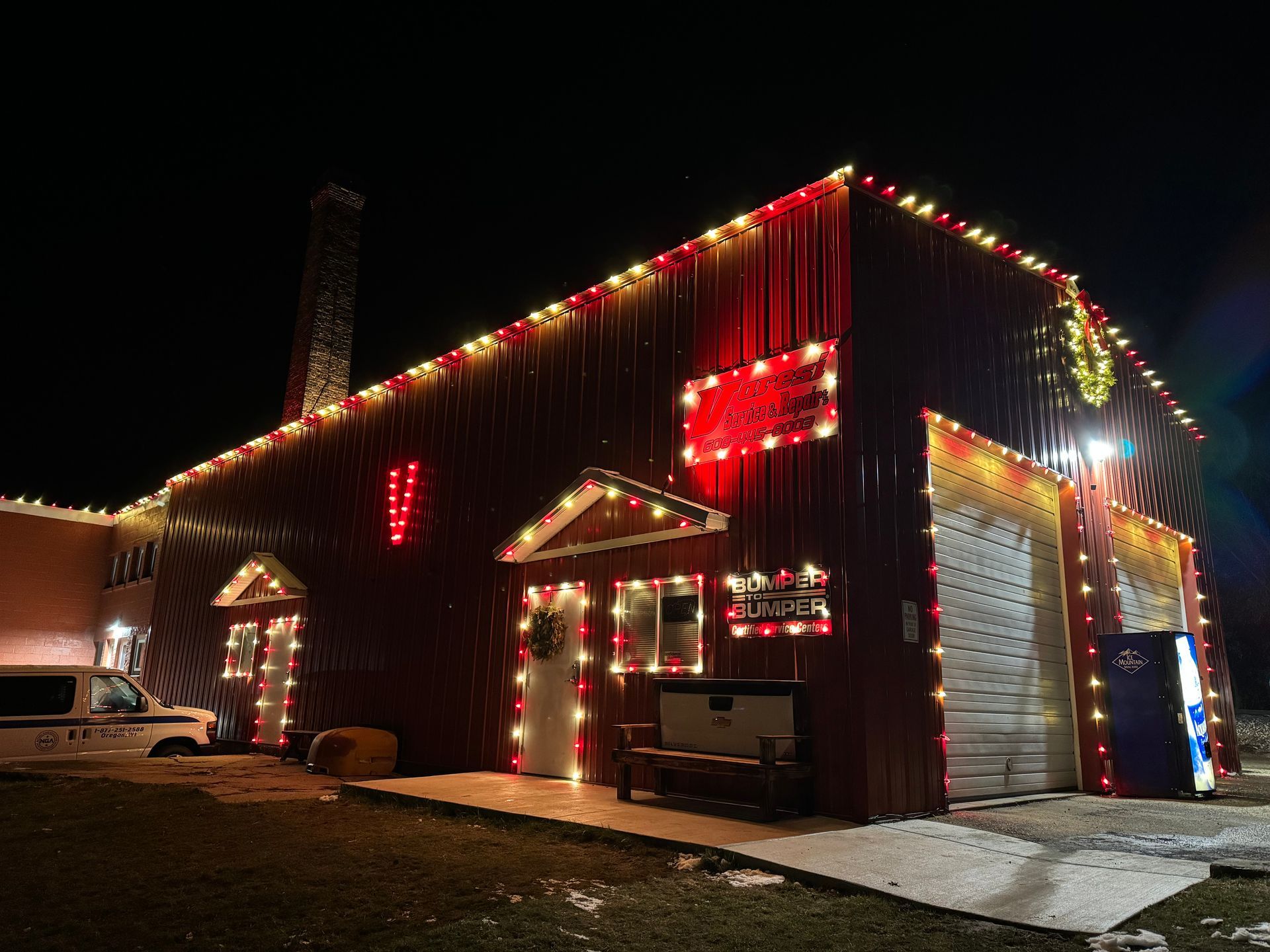 Barn at night outlined with red and white Christmas lights, viewed from the side.