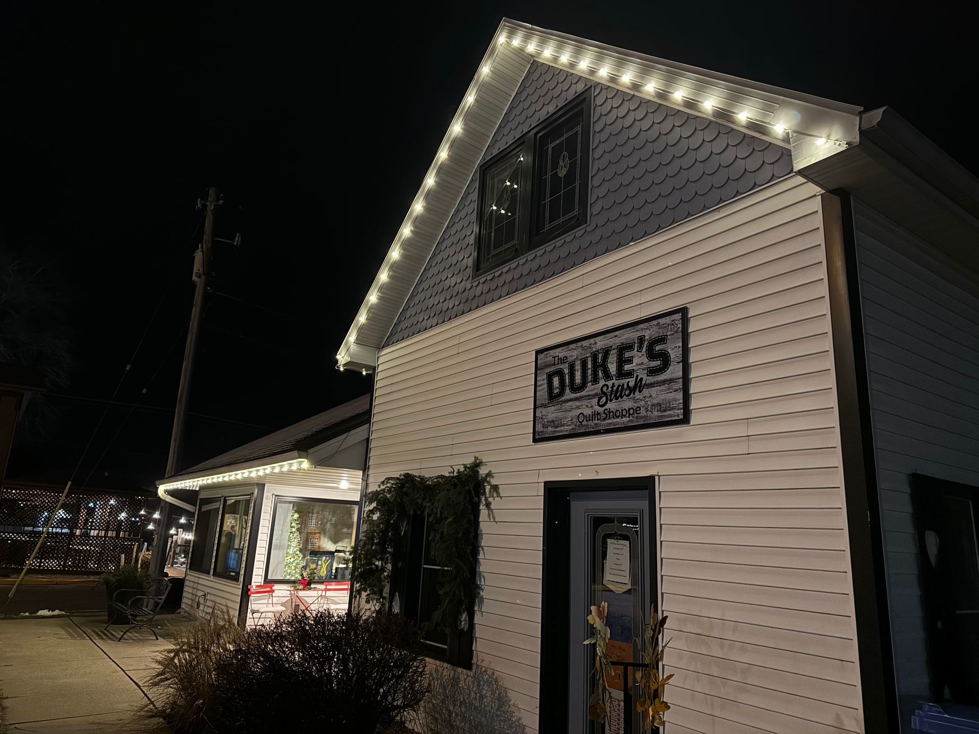 White building with a BURES sign lit by string lights at night on a street corner