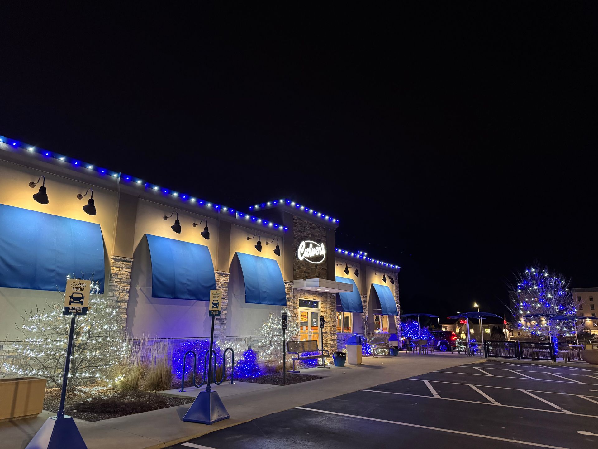Nighttime view of a lit building with blue holiday lights and an empty parking lot