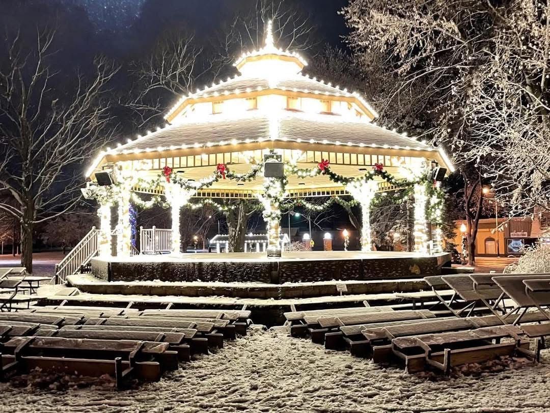 Illuminated gazebo at night with festive lights and snowy steps in a park