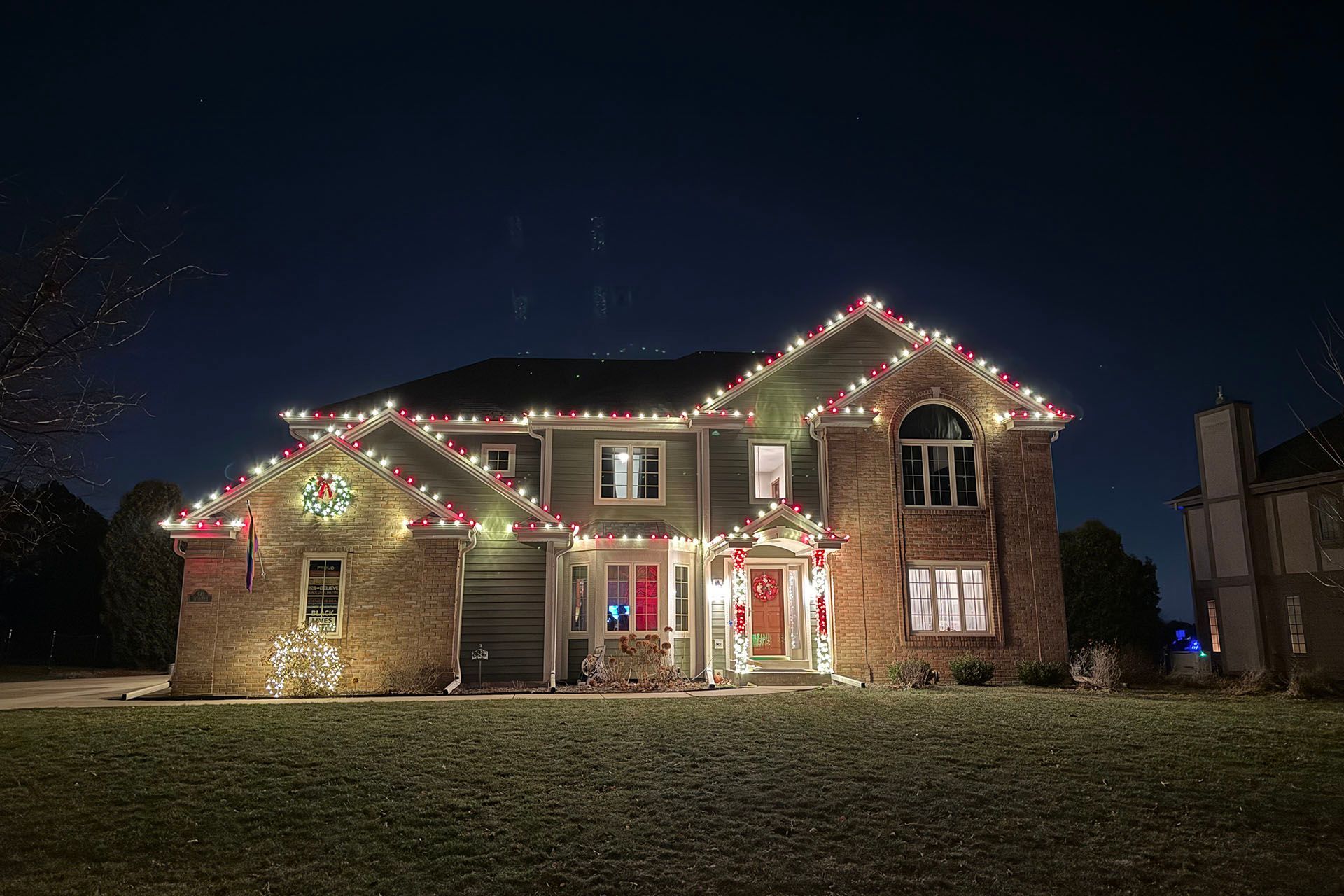 Brick house decorated with red and white Christmas lights at night
