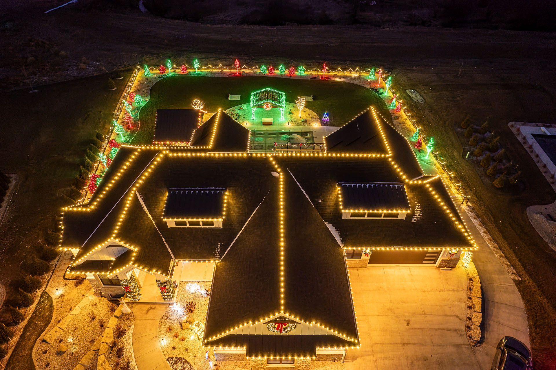 Aerial view of a house roof outlined with colorful Christmas lights at night