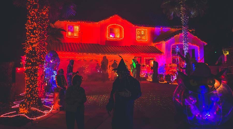 House glowing with red and purple Christmas lights, with silhouetted people standing in the yard at night