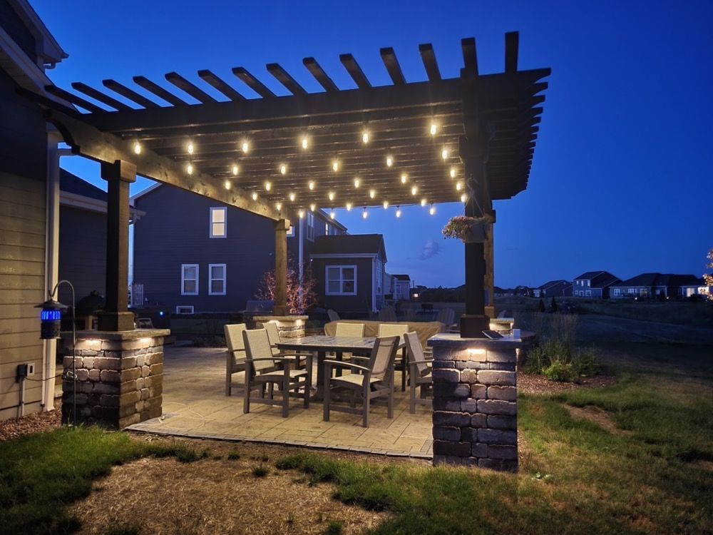 Backyard patio with string lights, pergola, and dining table at dusk
