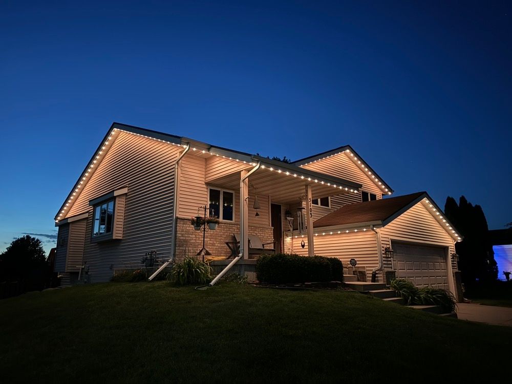 Two-story house at dusk with warm exterior lights and a blue evening sky