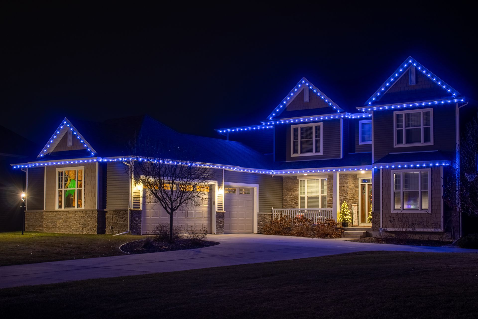 House at night outlined with blue and white holiday lights
