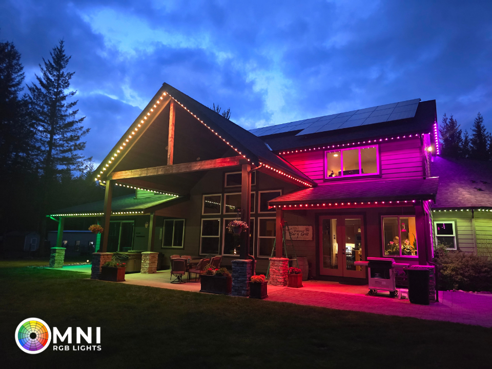 House exterior lit with colorful purple, pink, and green decorative lights at dusk