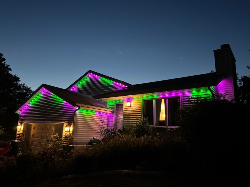 House at night outlined with purple and green holiday lights