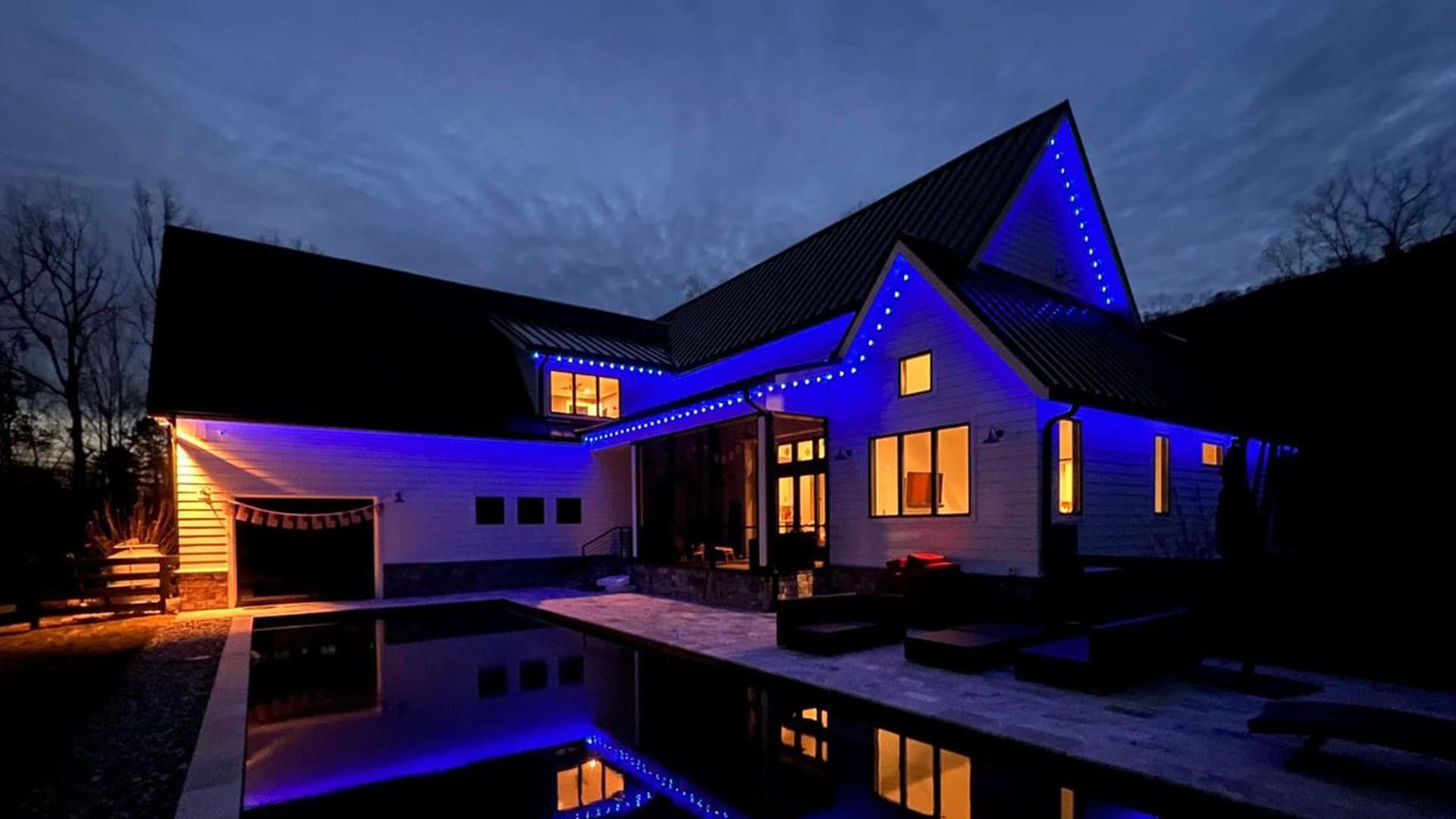 Modern house at night with blue and warm lights reflected in a still pool